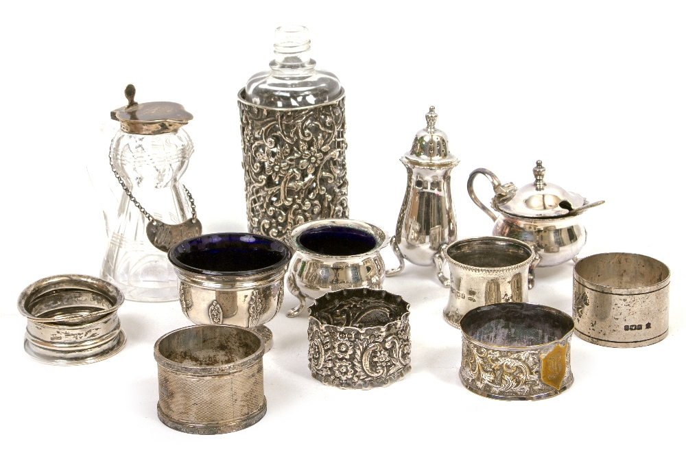 A SELECTION OF SILVER AND WHITE METAL NAPKIN RINGS, a silver condiment pot, faceted glass silver