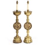 A PAIR OF GOTHIC STYLE BRASS ALTAR CANDLESTICKS later converted for electric use with pierced