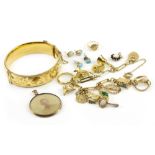 A YELLOW METAL CHARM BRACELET together with a gilt hinged bangle, a small brooch and further