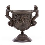 AN ANTIQUE BRONZE URN of classical form, decorated with cherubs and serpents, 17cm wide x 17cm high