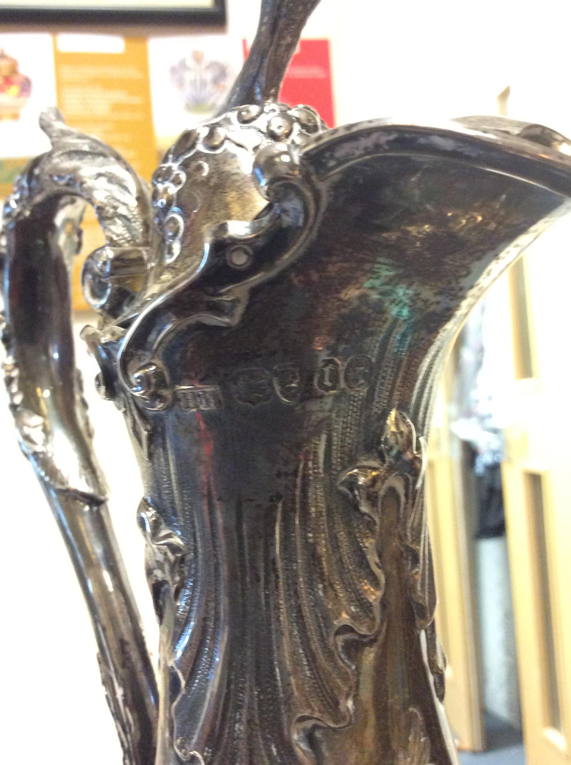 A VICTORIAN SILVER WATER JUG with repousse decoration and a scrolling handle on a circular base, - Image 6 of 10