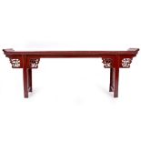 A CHINESE RED LACQUERED ALTER TABLE with pierced decoration either side of the rectangular legs,