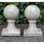 A PAIR OF CAST RECONSTITUTED STONE SPHERE FINIALS on square bases, each 23cm wide at the base x 39cm