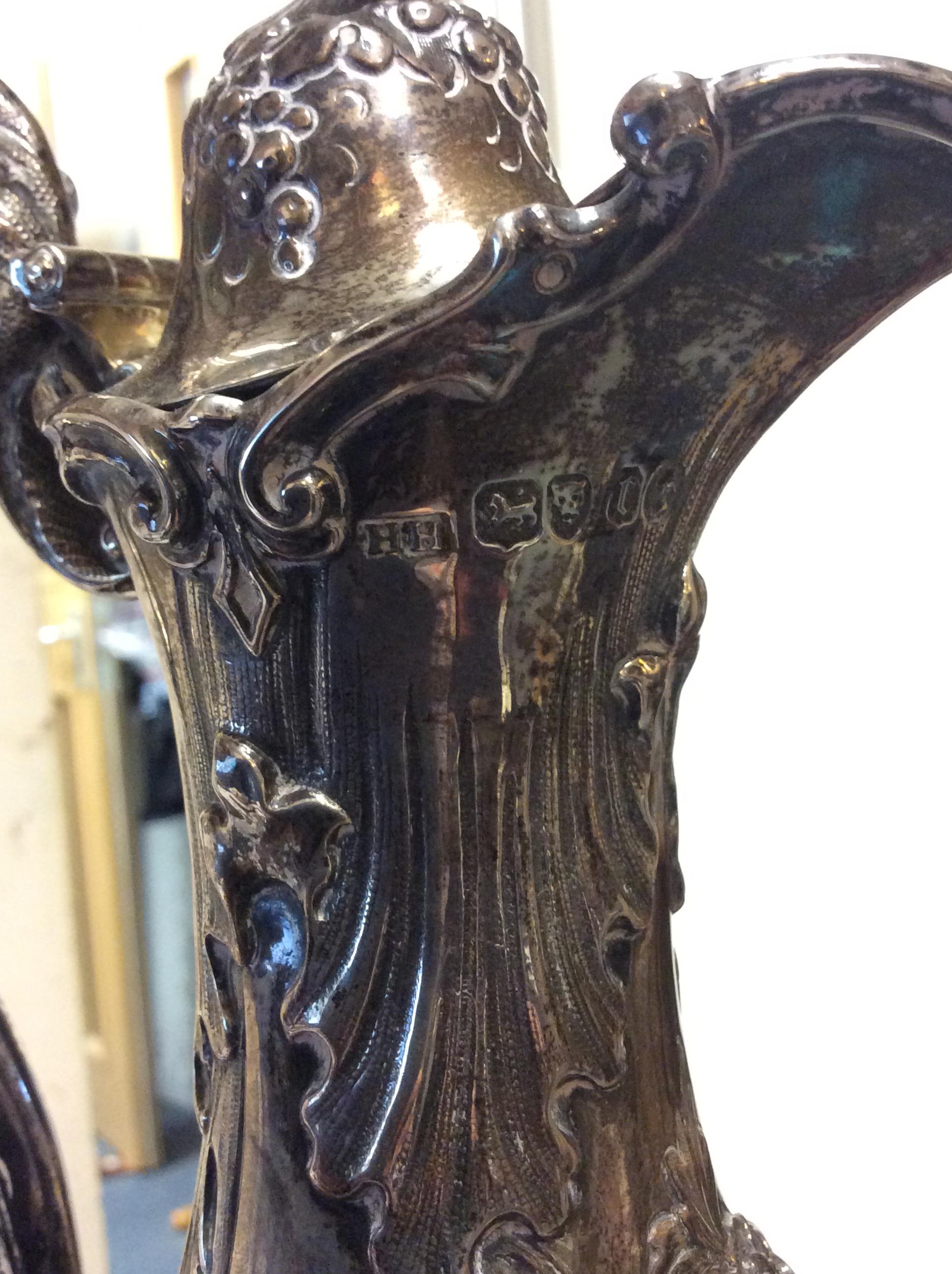 A VICTORIAN SILVER WATER JUG with repousse decoration and a scrolling handle on a circular base, - Image 7 of 10
