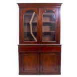 A VICTORIAN MAHOGANY GLAZED TOP BOOKCASE with arch glazed panels above fielded panel doors on a