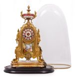 A 19TH CENTURY GILT SPELTER FRENCH MANTLE CLOCK with porcelain mounts, urn finial and on a shaped