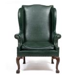 A GEORGE III STYLE LEATHERETTE UPHOLSTERED WING BACK ARMCHAIR with carved cabriole front legs,