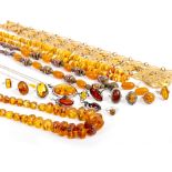 A QUANTITY OF AMBER to include amber pendants, bead necklaces, gilt metal filigree belt etc (a