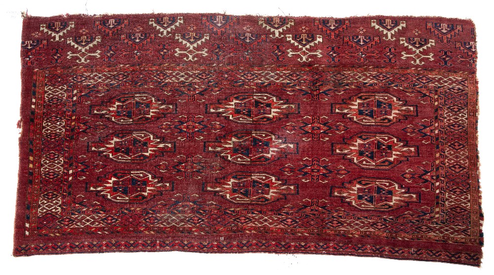 A LATE 19TH / EARLY 20TH CENTURY TEKKE TURKMEN RED GROUND RUG with three rows of guls, 133cm x 71cm