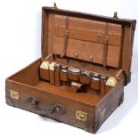 A GEORGE V GENTLEMAN'S LEATHER SUITCASE with fitted interior to include six silver bottles and jars,