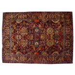 AN ORIENTAL RED GROUND FLOWER DECORATED RUG the central field densely patterned with stylised