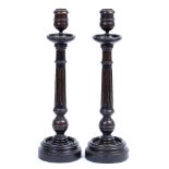 A PAIR OF DARK STAINED TURNED WOODEN CANDLESTICKS with fluted stems and spreading circular bases,