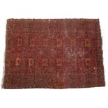 A SMALL RED GROUND BALUCHI RUG with twelve medallions to the central field within a multiple