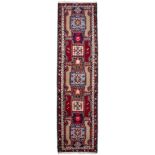 AN ORIENTAL BEIGE, RED AND BLUE GROUND RUNNER with geometric motifs and floral banded