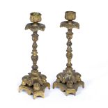 A PAIR OF ANTIQUE GILT METAL CANDLESTICKS the triform bases cast with female masks, 9cm wide x 22.