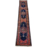 A MID 20TH CENTURY PERSIAN STYLE RED AND BLUE GROUND RUNNER with a banded border, having geometric