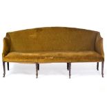 AN ANTIQUE SETTEE with arching back, ring turned legs terminating in club feet and brass casters,