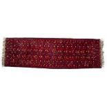 A BURGUNDY GROUND ORIENTAL RUNNER 300cm long x 83cm wide