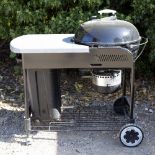 A WEBER BARBECUE with domed cover and on a wheeled stand, 117cm long x 65cm deep overall