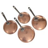 A GRADUATED SET OF FOUR COPPER SAUCEPAN LIDS with iron handles, the largest 23cm diameter