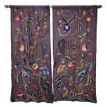 A PAIR OF 19TH CENTURY CREWEL WORK PANELS OR CURTAINS with wools on an aubergine linen depicting