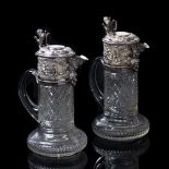 A PAIR OF CUT GLASS CLARET JUGS the silver plated mounts surmounted with hinged lids, with lion