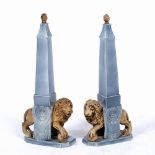 A PAIR OF POTTERY ORNAMENTS in the form of obelisks, with lion supports, 32cm wide x 67.5cm high (