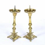 A PAIR OF ANTIQUE BRASS PRICKET CANDLESTICKS with turned stems and triform bases, 10cm diameter x