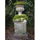 A CARVED STONE SMALL URN with gadrooned body together with a carved stone plinth with panelled