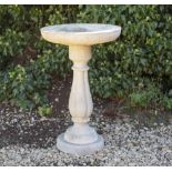 A CAST RECONSTITUTED STONE CIRCULAR BIRD BATH on reeded baluster support, 45cm diameter x 71cm high