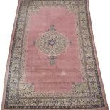 A MIDDLE EASTERN PINK GROUND CARPET with a banded border and a central foliate motif, 580cm x 314cm