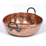 A LARGE COPPER BOWL with looping iron handles, 52cm diameter