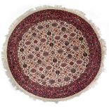 A CIRCULAR WHITE GROUND ORIENTAL RUG with geometric fall decoration to the central field within a