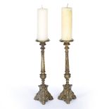 A PAIR OF ANTIQUE PRICKET CANDLESTICKS with reeded stems and masks applied to the triform bases,