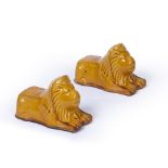 A PAIR OF HONEY GLAZED TERRACOTTA SASH WINDOW SUPPORTS in the form of recumbent lions, 15cm long x