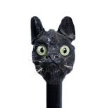 AN EBONISED WALKING STICK with a carved wooden top in the form of a cat's head with glass eyes, in