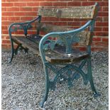 A GARDEN BENCH with green painted cast iron leaf decorated ends and wooden back and seat, 151cm wide