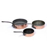 A SET OF THREE COPPER SAUTÉ PANS with wrought iron handles, the largest 31cm diameter