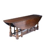 AN OAK DROP LEAF WAKE TABLE with turned supports, 228cm wide x 143cm deep x 76cm high