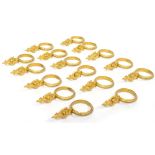 A COLLECTION OF SIXTEEN GILT BRASS CURTAIN RINGS with decorative ornament, each curtain ring 7cm