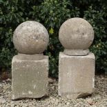 A PAIR OF CARVED LIMESTONE BALL FINIALS 27cm diameter each with a rectangular stone base (2)