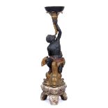 A COMPOSITE TORCHERE in the form of a Blackamoor figure riding on the back of a dolphin,
