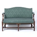 A CHIPPENDALE STYLE MAHOGANY CAMEL BACKED SETTEE with carved decoration to the arm supports and