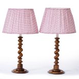 A PAIR OF TABLE LAMPS with turned treen barley twist supports, on spreading circular bases and