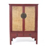 A CHINESE RED PAINTED CUPBOARD with rattan inset doors over two drawers, 110cm wide x 51cm deep x