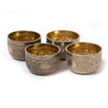 A SET OF FOUR PARCEL GILT SALTS with engraved Indian decoration, marks for London 1885, each 5.5cm