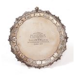 AN EDWARDIAN SILVER MILITARY PRESENTATION SALVER with decorative edge, claw and ball feet and