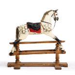 A CARVED PAINTED WOODEN ROCKING HORSE with leather saddle, on a pine frame, 124cm long x 113cm high