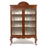 A WALNUT BOOKCASE in the Georgian manner, with arching top, glazed doors and on a stand with shell