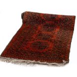 AN EASTERN WOVEN HALLWAY RUNNER with nine medallion designs on a red ground, 287cm x 79cm